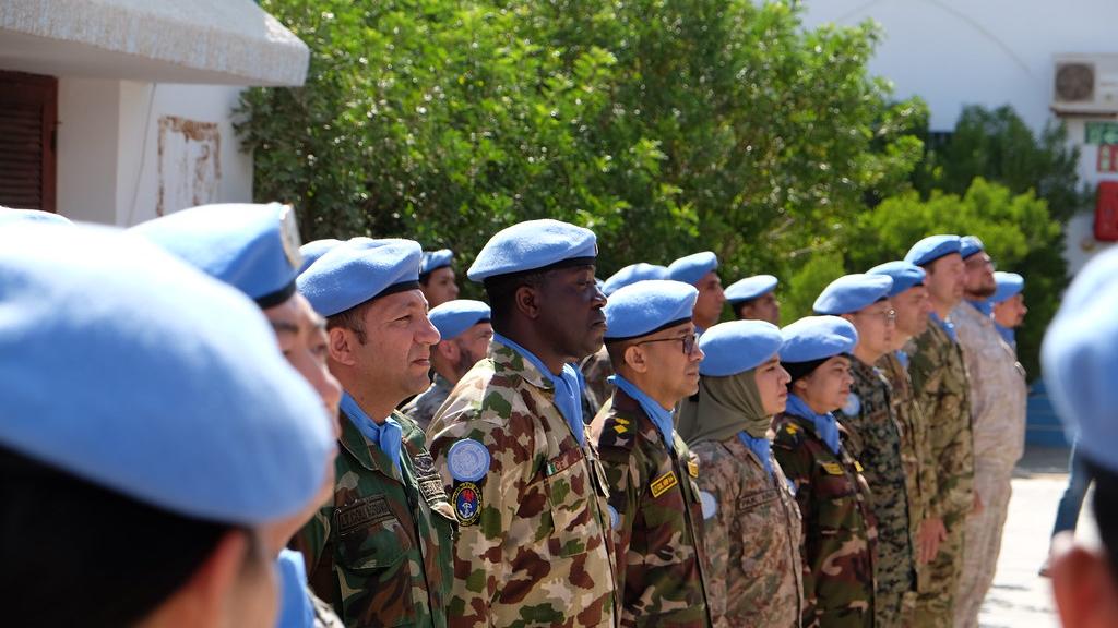 UN soldiers stand in a row wearing blue berets
