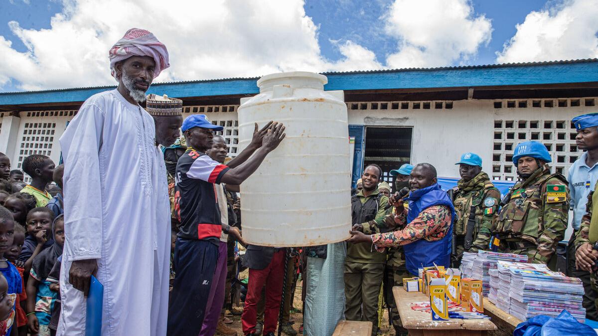 A group lifts equipment outdoors.