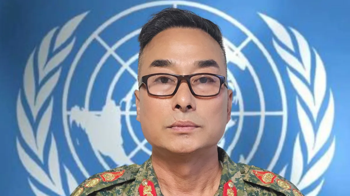 Man wearing military uniform and glasses in front of UN flag