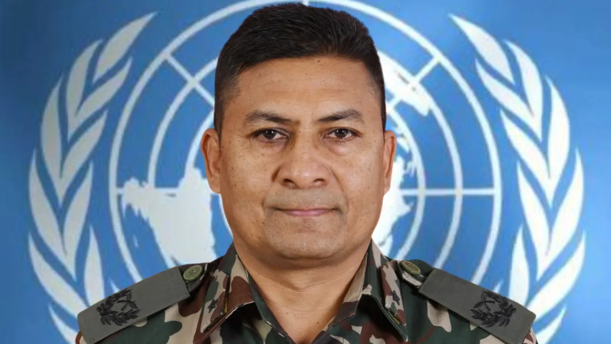 Man in military uniform standing in front of UN Flag