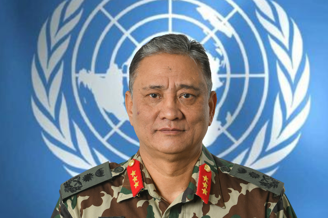 A headshot of a man in military uniform against a background showing the UN logo