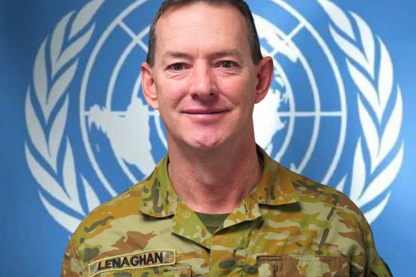 A headshot of a man in military uniform standing in front of the UN logo